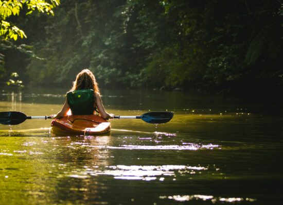 Tourisme - une femme touriste de dos, dans un kayak, sur une rivière - eau